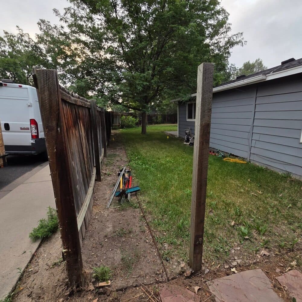 Wooden fence posts with gate framework under construction in a residential yard