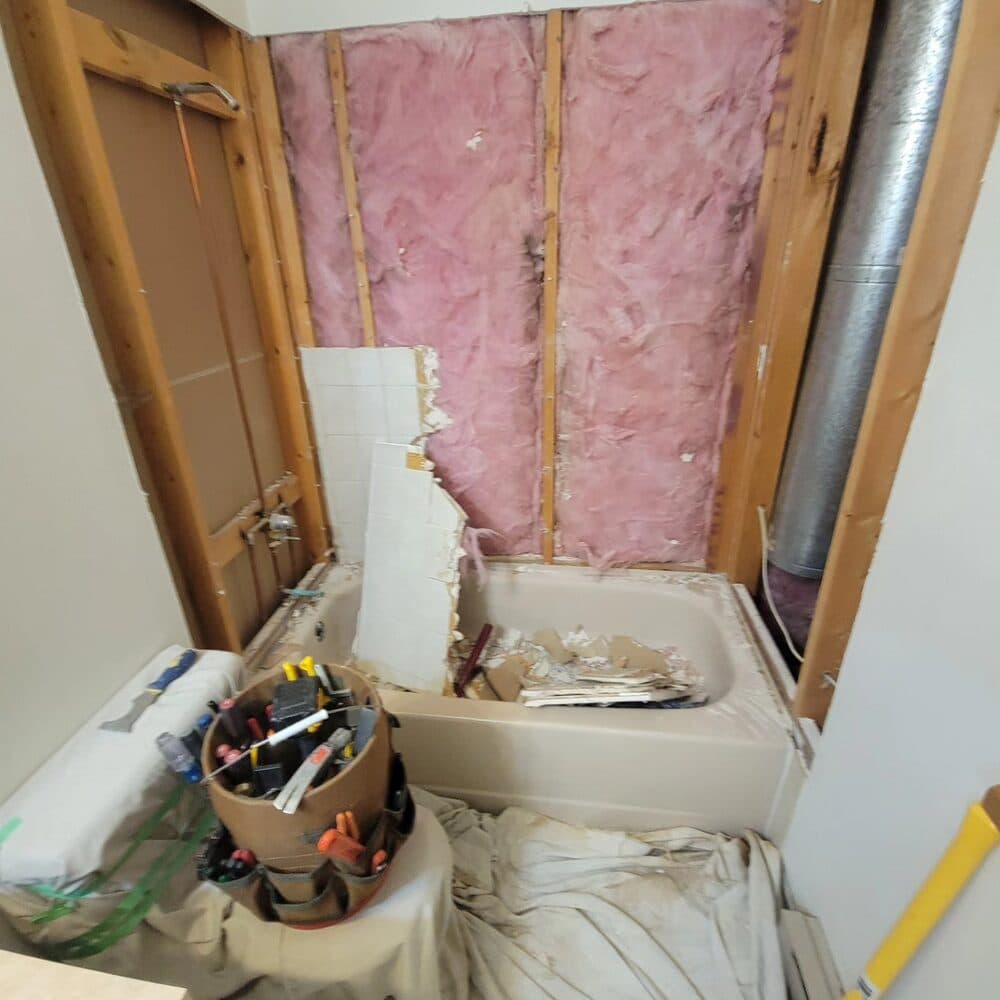 Interior wall framing in progress showing studs, insulation, and electrical conduit